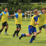 Happy kids enjoying soccer and running together during JP soccer summer camp.