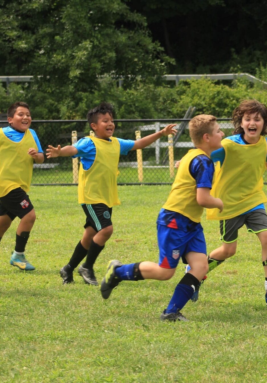 Happy kids enjoying soccer and running together during JP soccer summer camp.
